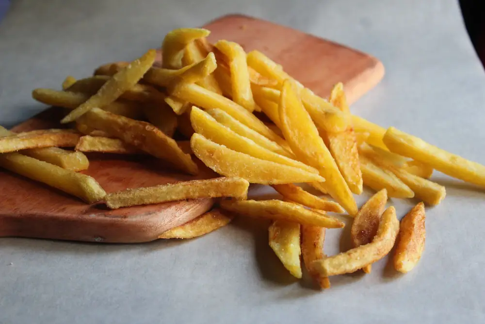 Golden homemade chips piled on a wooden board