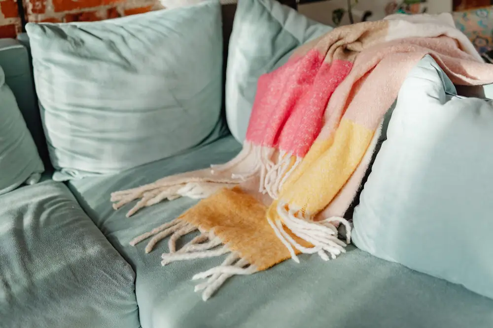 Striped throw blanket draped over a pale green sofa with cushions
