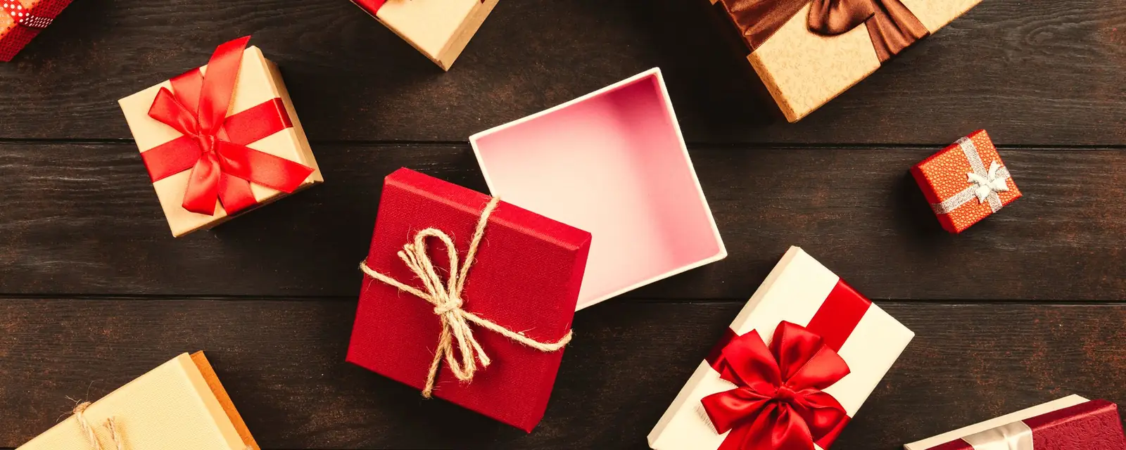 Gift boxes tied with red and gold ribbons on a dark wooden table
