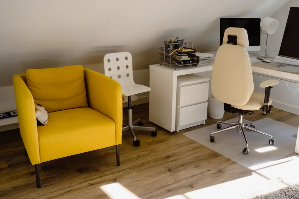 Bright home office corner with a white swivel chair at a desk and a yellow armchair