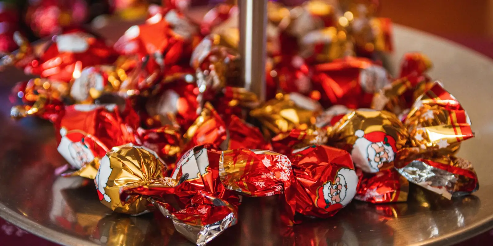 A pile of foil-wrapped Christmas chocolates in red and gold on a silver stand