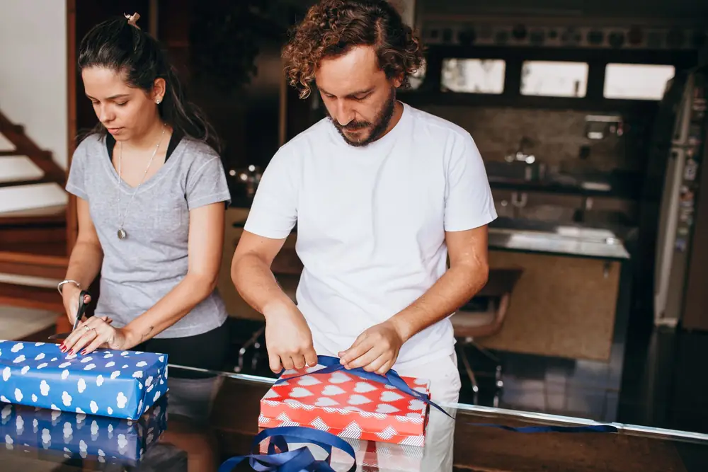 Couple wrapping presents on a kitchen worktop