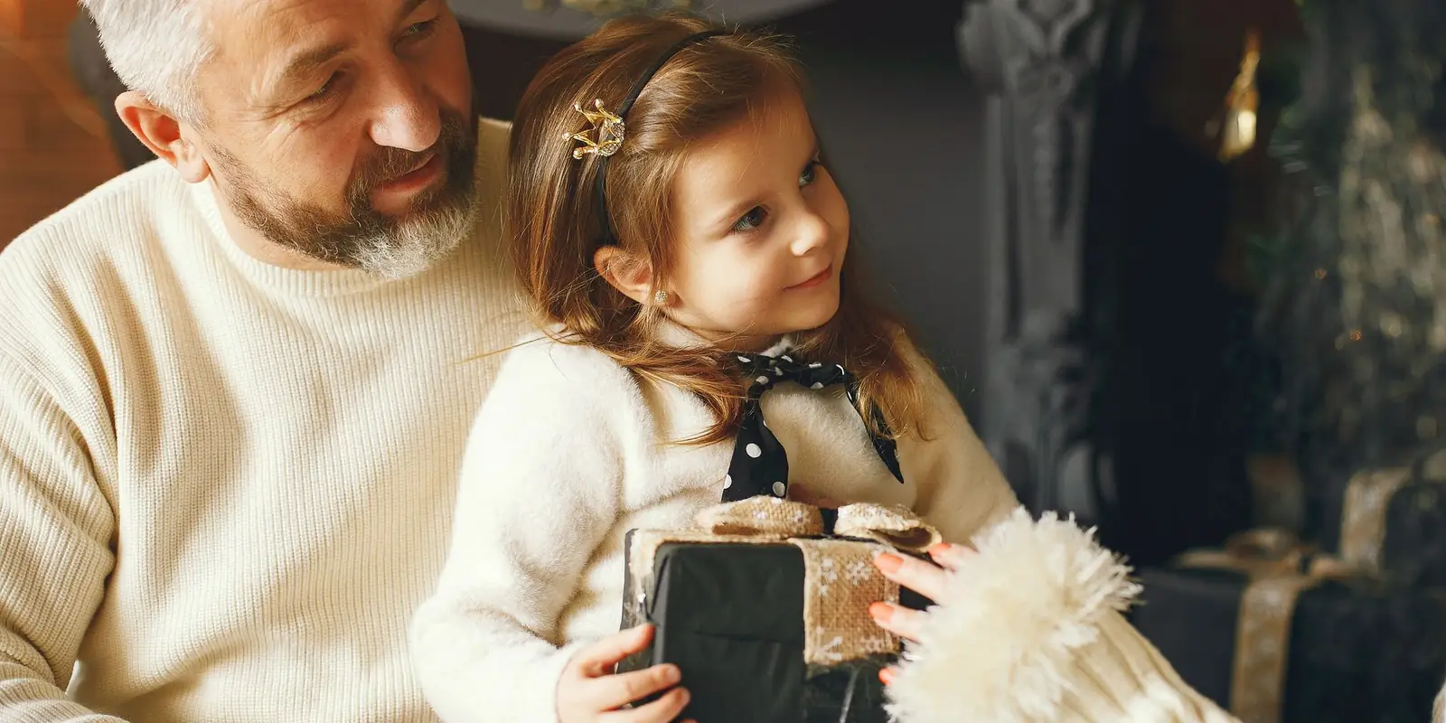 Older man and a young girl exchanging a wrapped Christmas present
