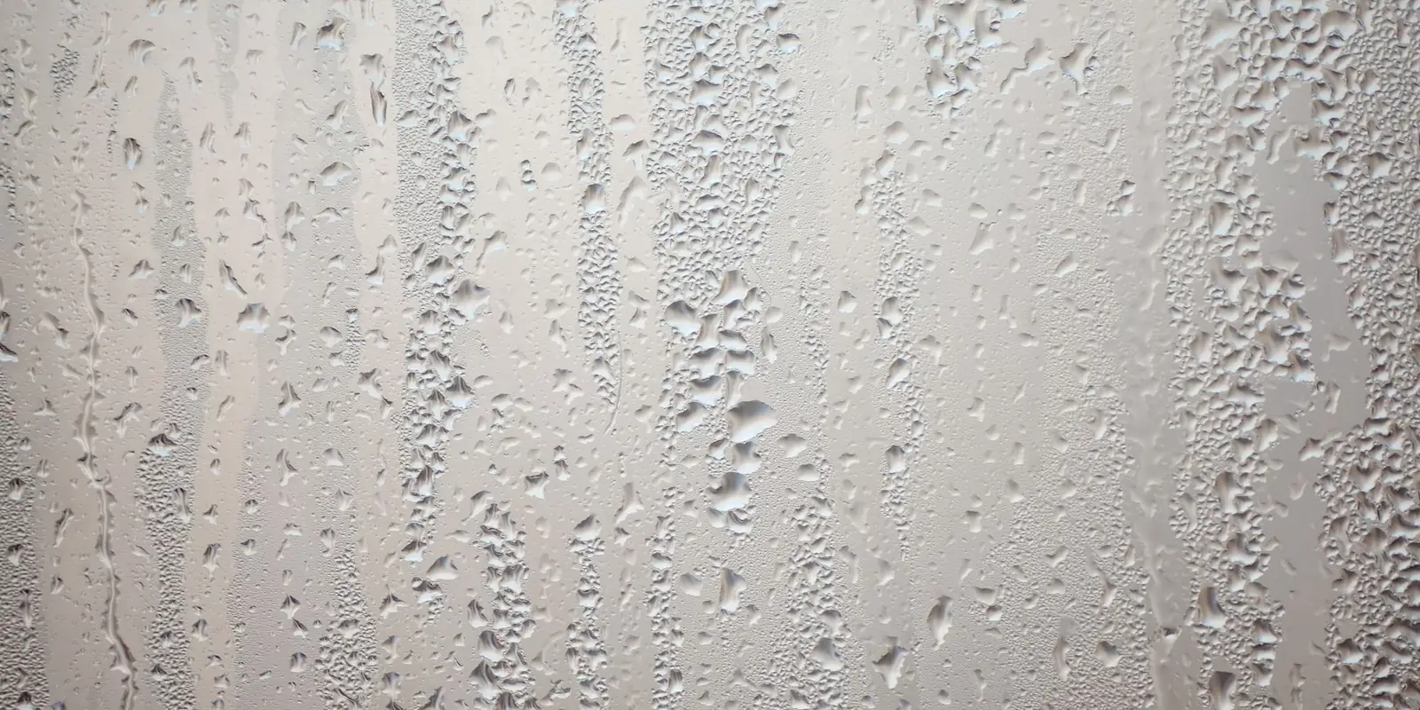 Condensation droplets running down the inside of a window pane