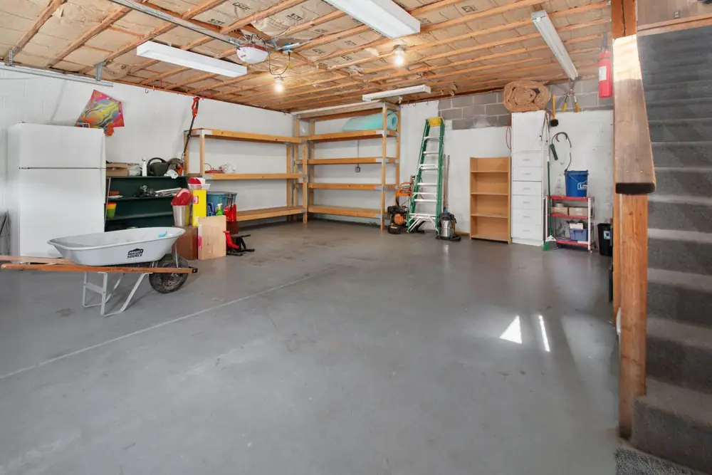 Tidy garage with storage shelves, a workbench and a wheelbarrow