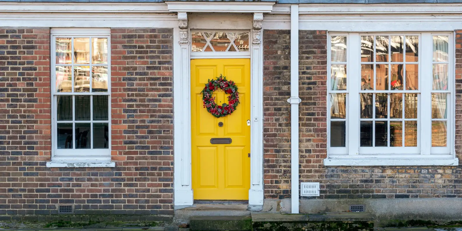 Brick terraced house with a yellow front door and a wreath