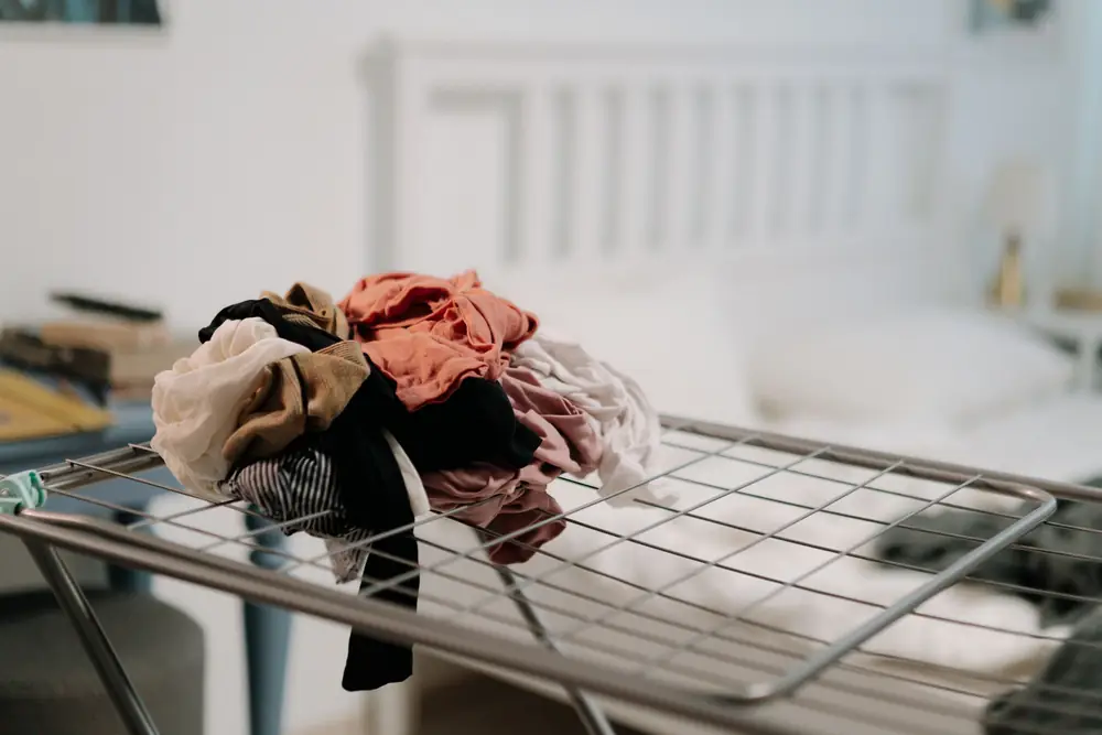 Clothes spread out on a metal drying rack in a bright room