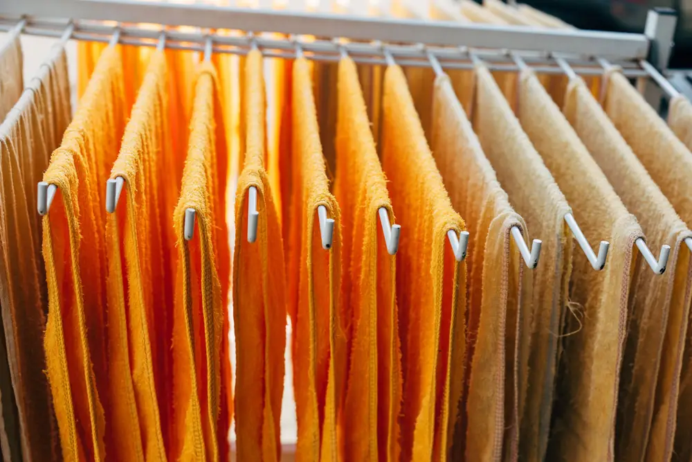 Orange and beige towels hung in single layers on an indoor drying rack