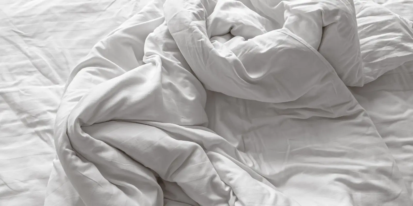 A thick, rumpled white duvet on a bed