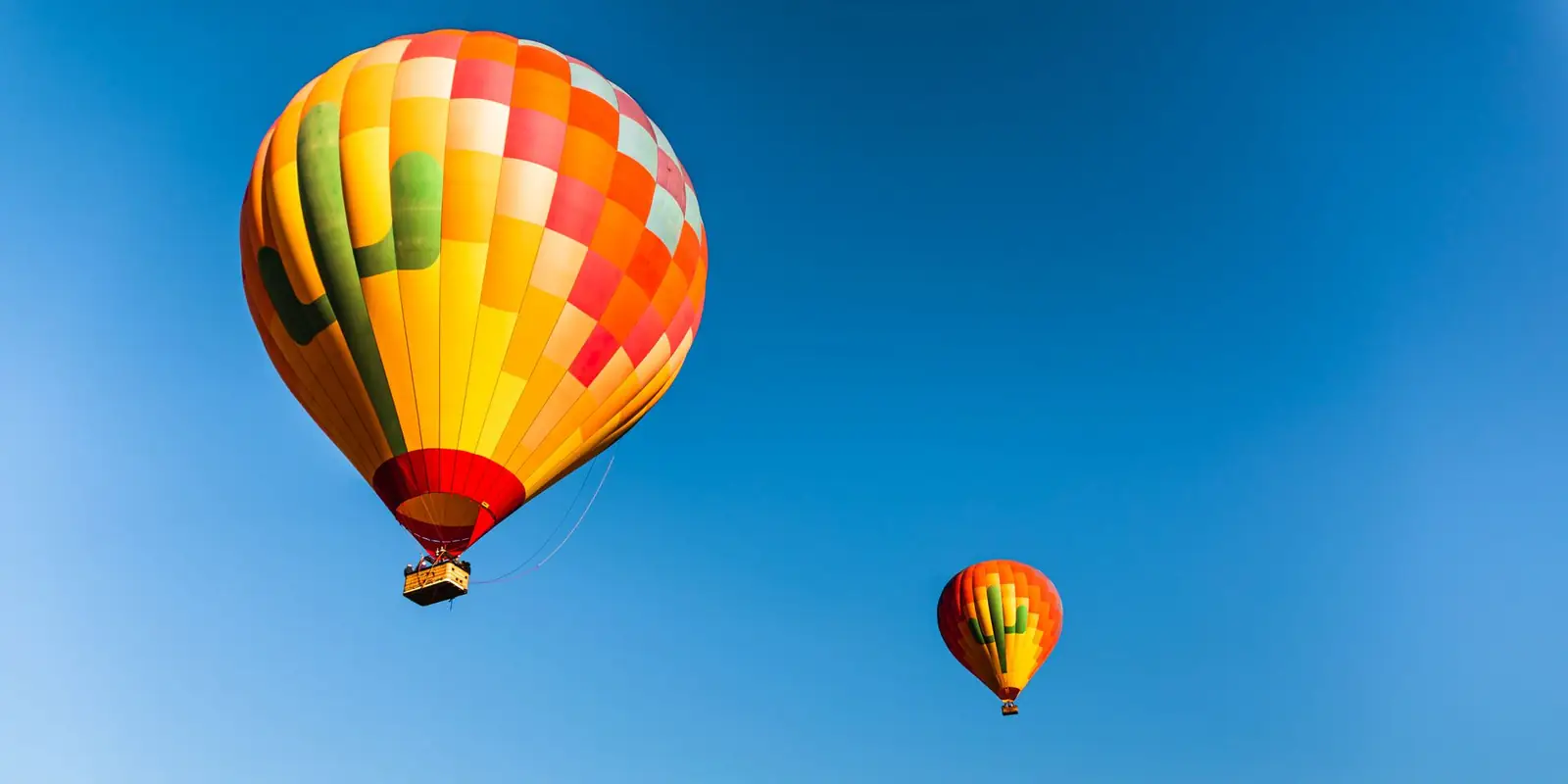 Three colourful hot air balloons drifting in a clear blue sky