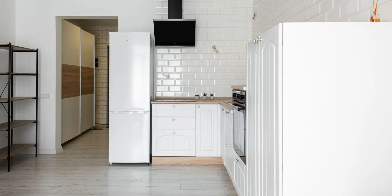 Bright white kitchen with a tall freestanding fridge freezer beside the cupboards