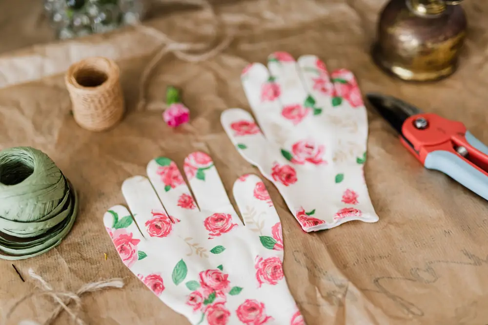 Floral garden gloves, a pruner and a ball of twine laid on brown craft paper
