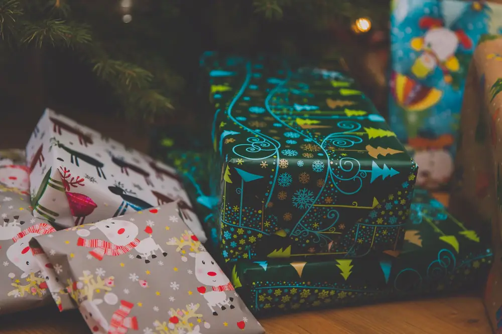 Colourfully wrapped Christmas presents under a decorated tree
