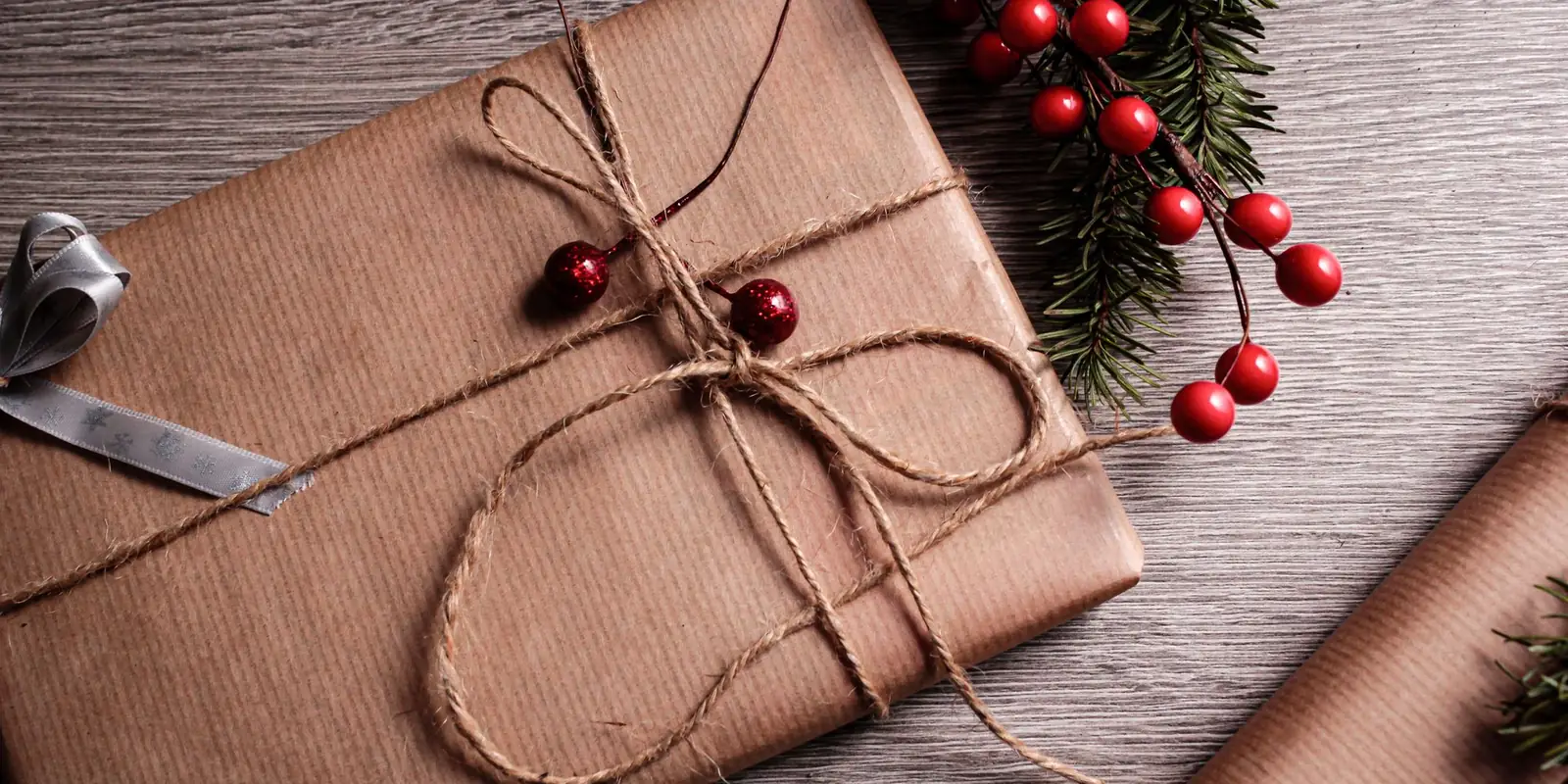 Christmas present wrapped in brown paper and twine with holly berries
