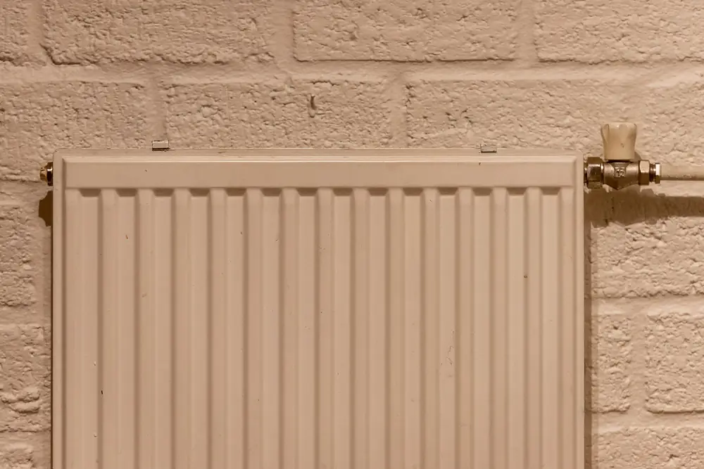 White panel radiator mounted on a painted brick wall