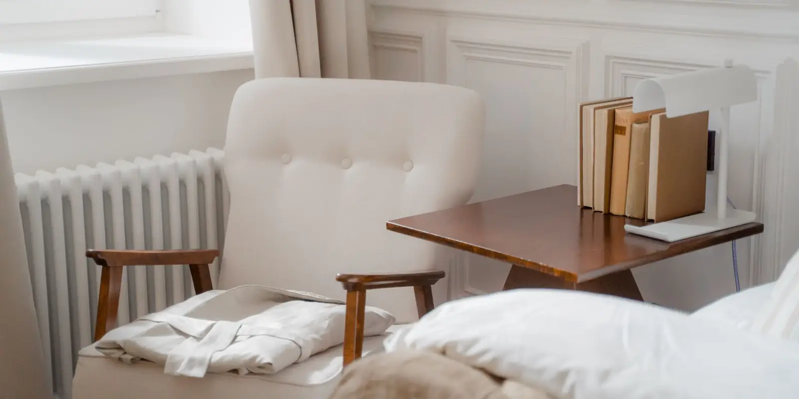 Bright bedroom with an armchair beside a white radiator under the window