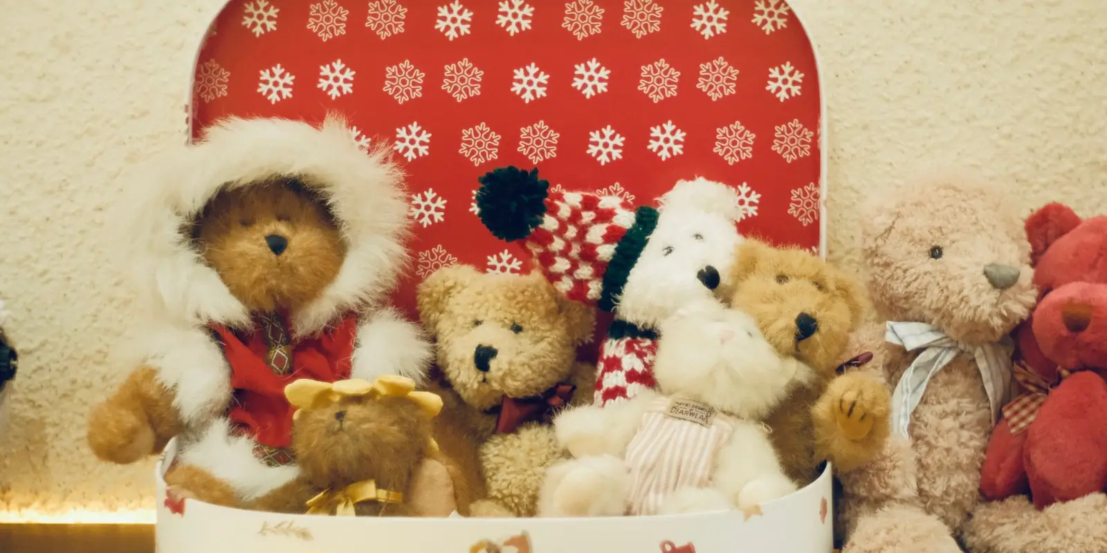 Teddy bears in festive hats and scarves sitting in a red snowflake gift box