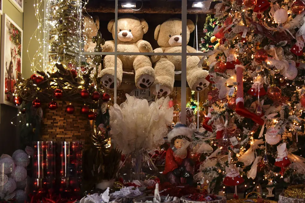 Teddy bears on a shelf in a shop decorated with Christmas trees and lights