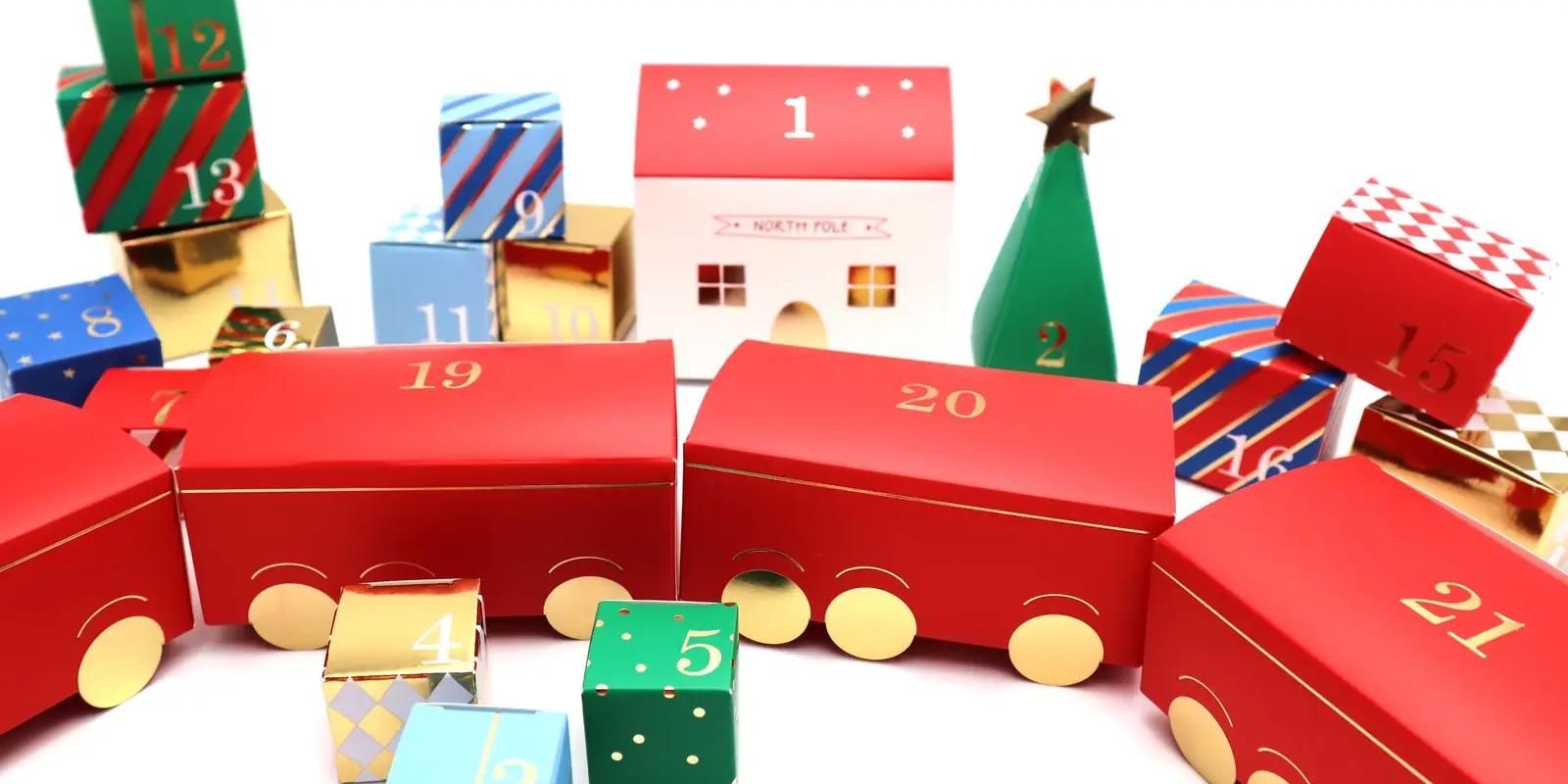 Numbered red, green and gold advent gift boxes shaped like a train, with a little North Pole house and a paper Christmas tree