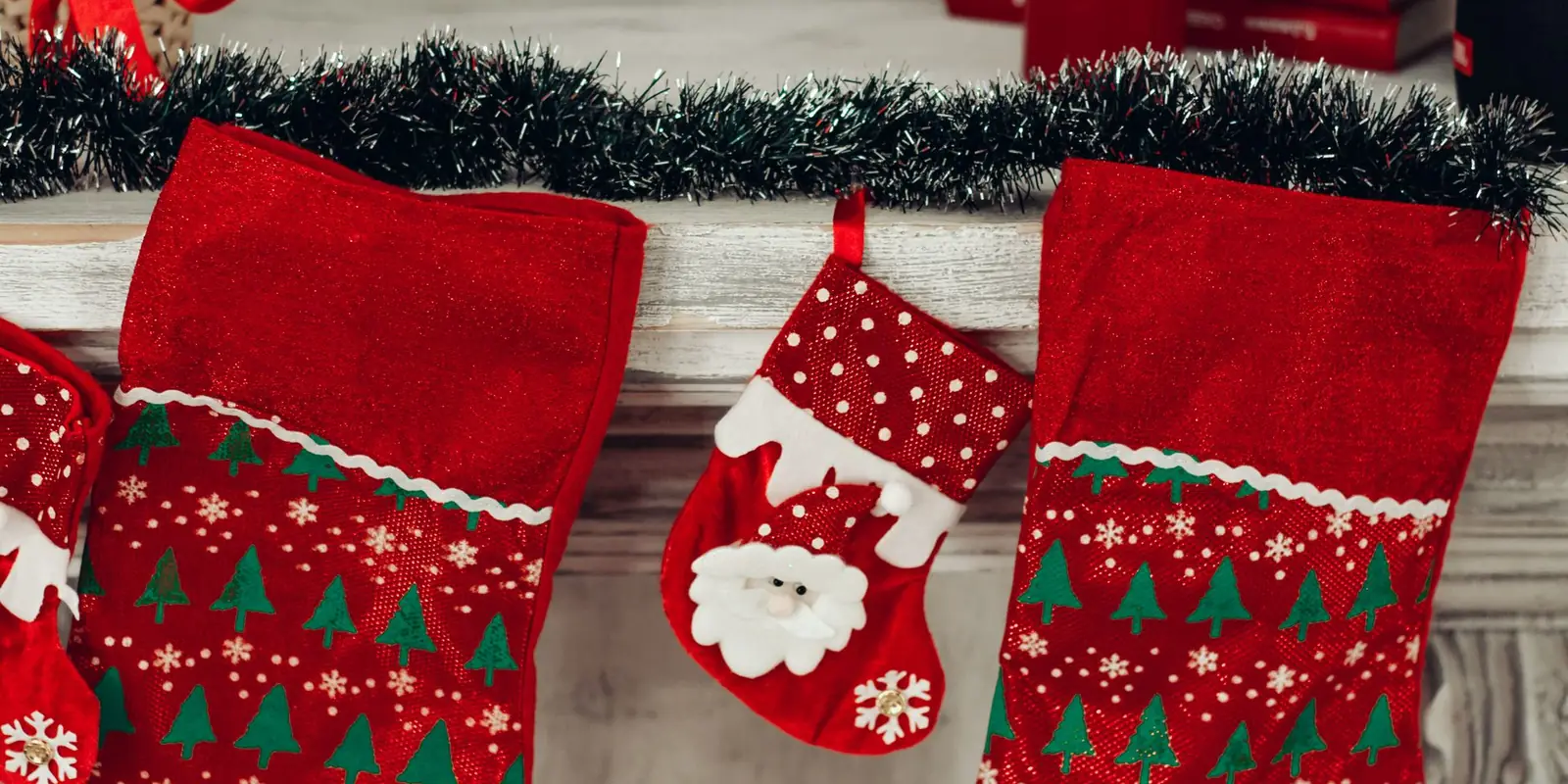 Three red and green Christmas stockings hanging on a wall