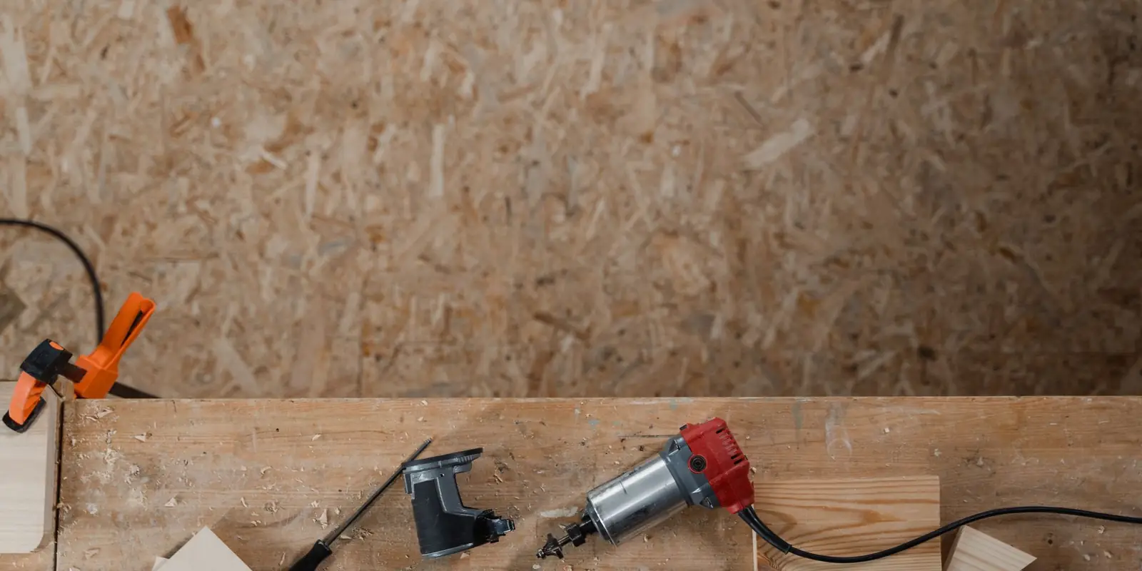 Power tools and wood offcuts on a plywood workbench