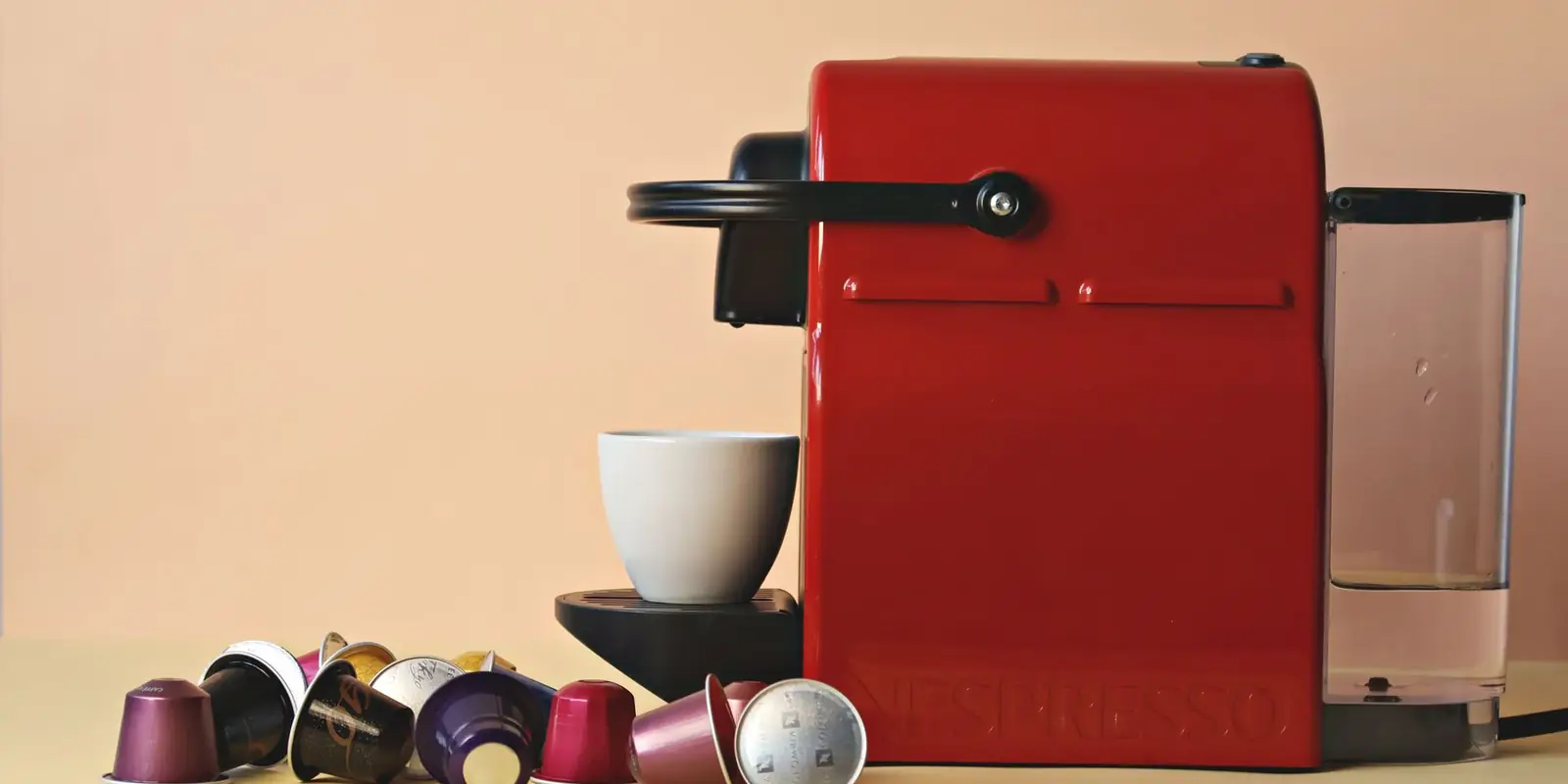 A red capsule coffee machine with coffee capsules and a cup