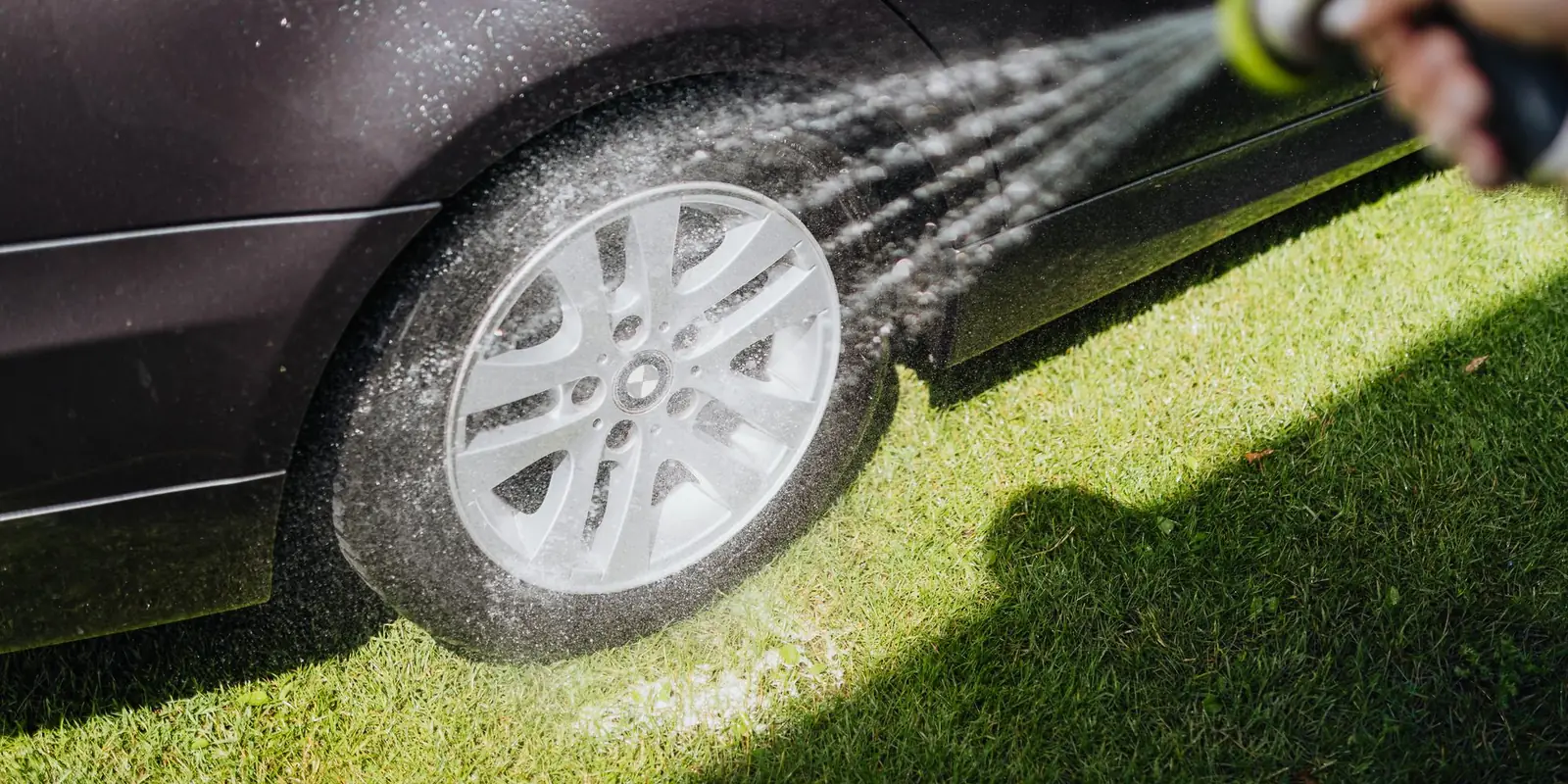 Spraying water onto a car wheel parked on a lawn