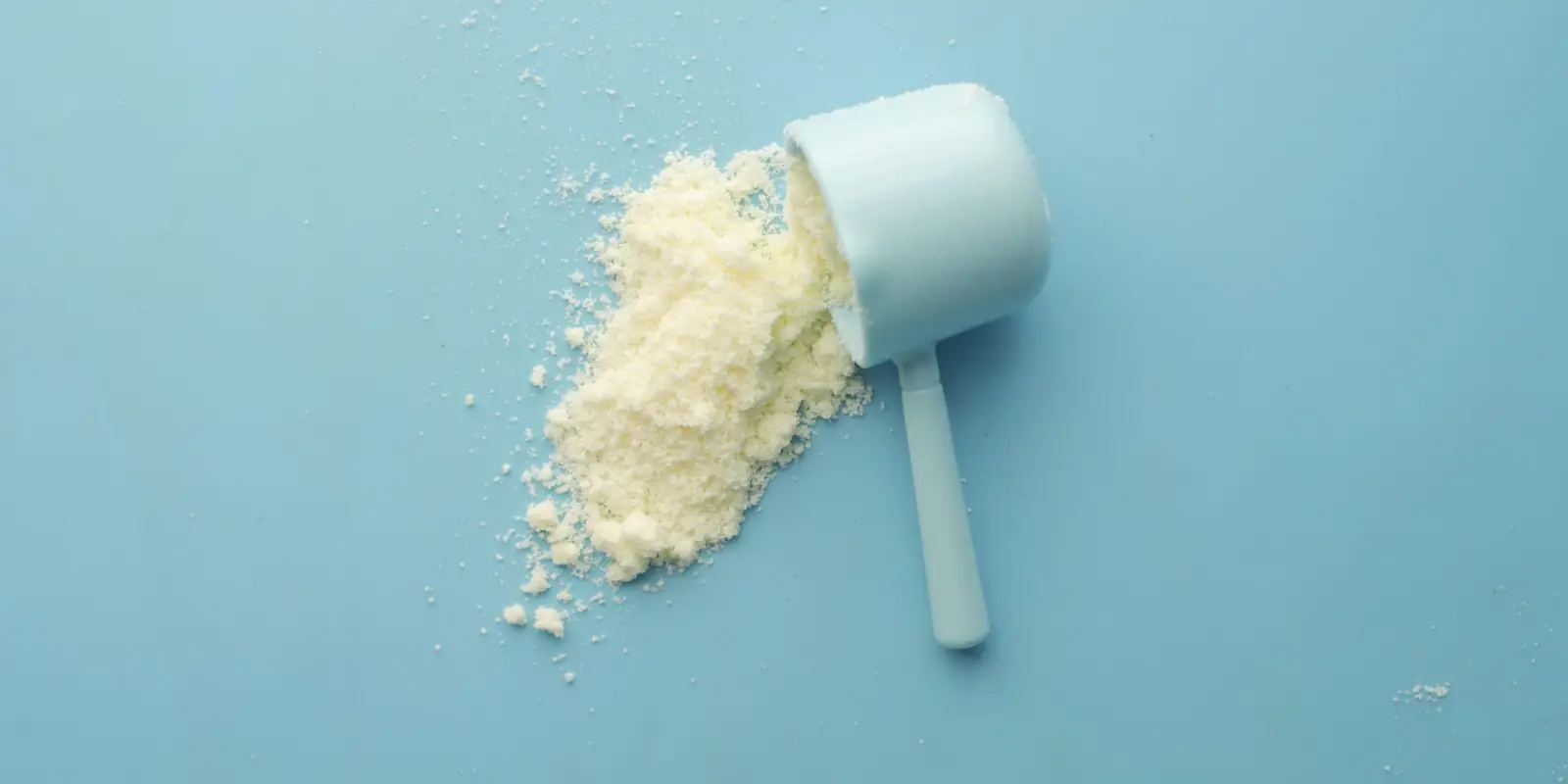 White powder and a measuring scoop on a plain blue background