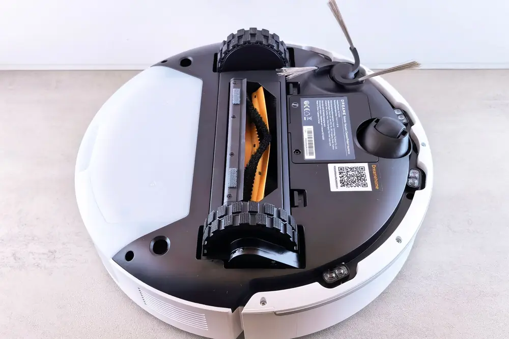Underside of a robot vacuum showing its main brush, side brush and wheels