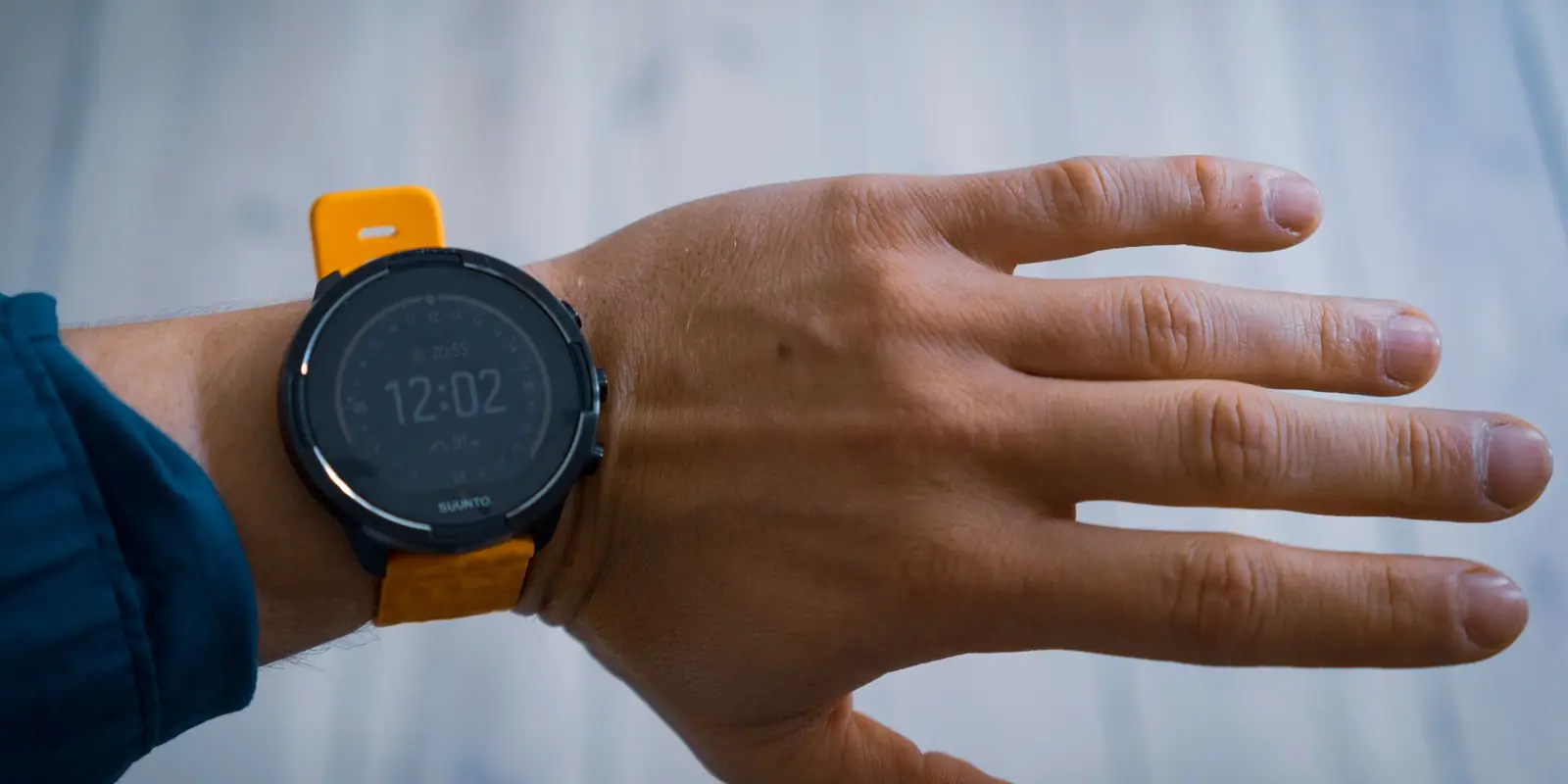 Black sports watch with an orange strap on an outstretched wrist