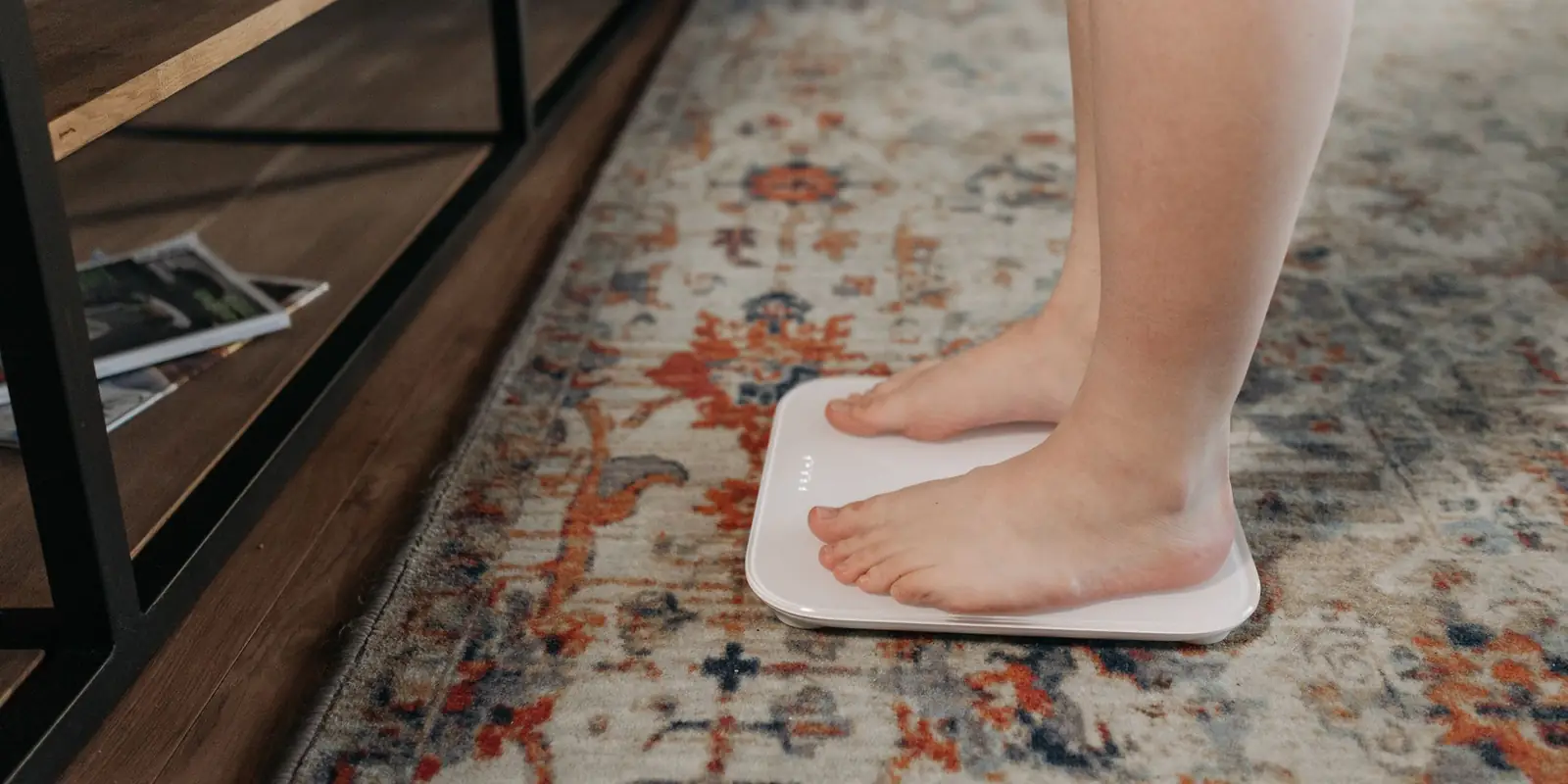 Bare feet on a white glass smart scale on a patterned rug