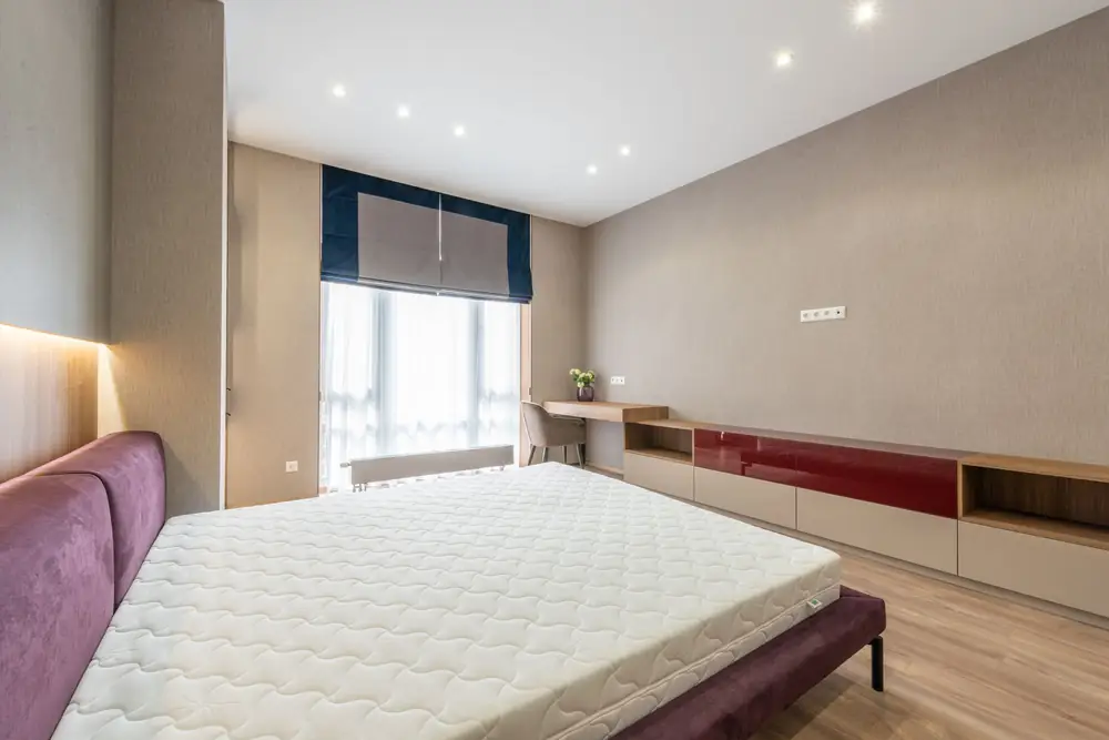 Bare white mattress on a bed frame in a modern bedroom