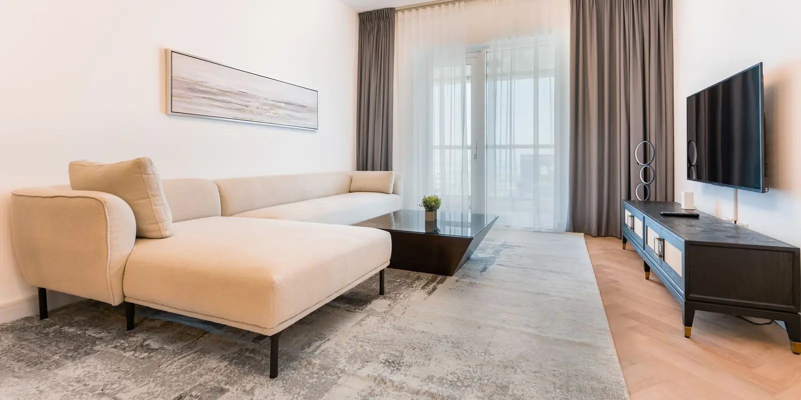 Bright living room with a cream sofa, rug and a TV on a low unit by the window