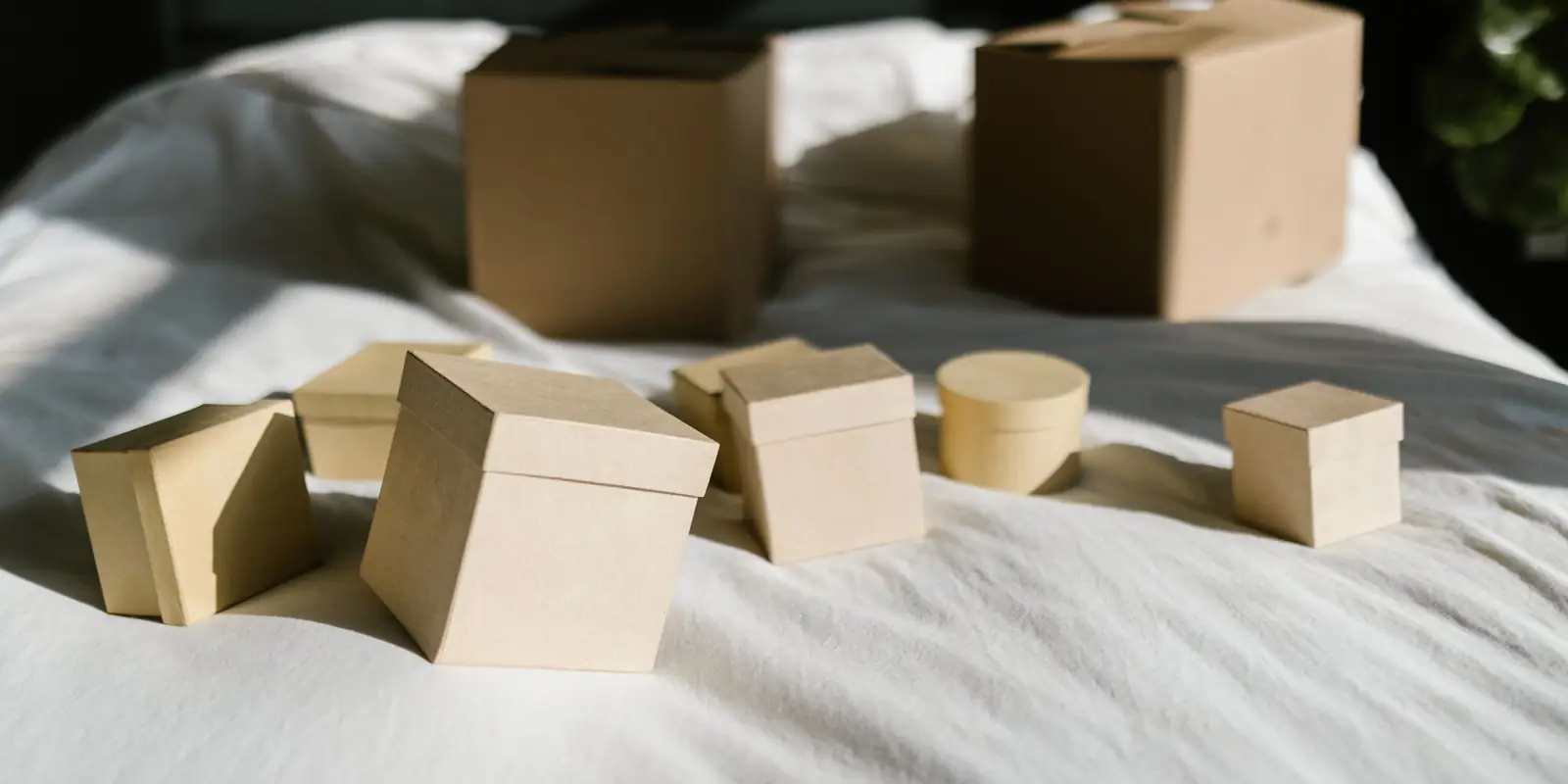 Small cardboard storage boxes with lids arranged on a white bed