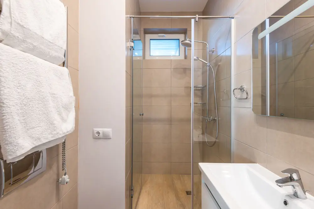 Modern bathroom with a glass shower screen, beige tiles and a sink