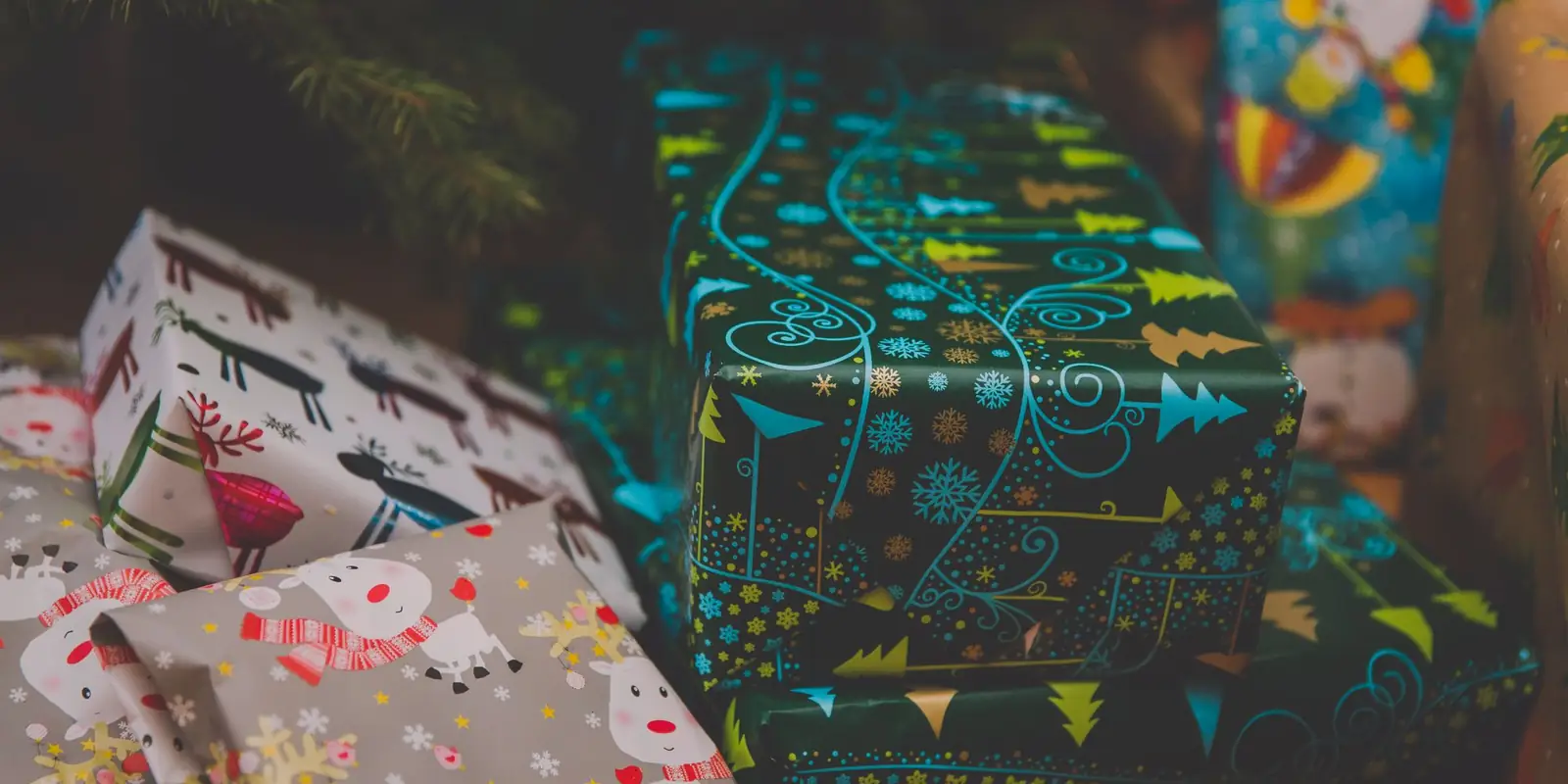 Colourfully wrapped Christmas presents under a decorated tree
